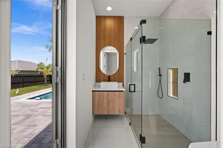 Modern bathroom featuring a walk-in glass shower with black fixtures, a floating wood-finish vanity, and a wood-slat accent wall