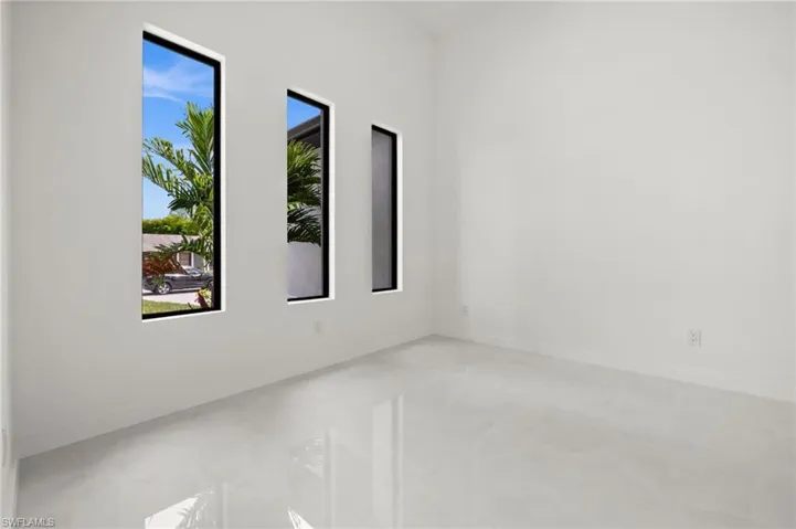 Interior room featuring white walls, high ceilings, and light-toned tile flooring