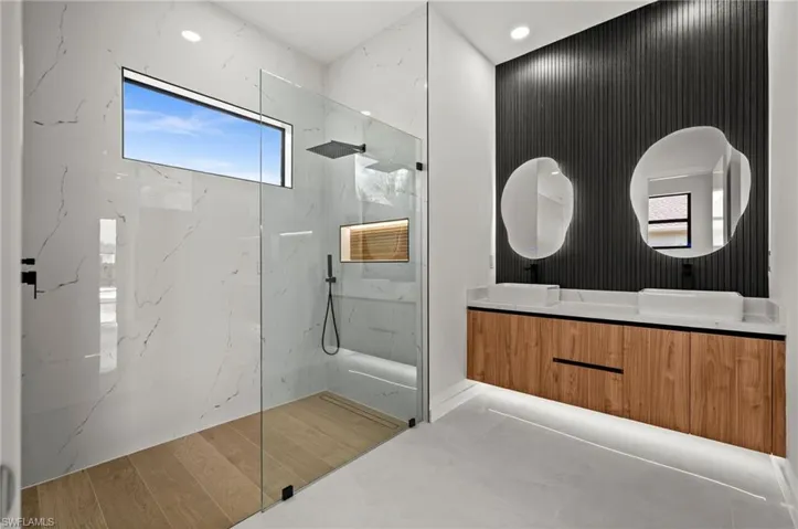 Contemporary bathroom featuring a spacious glass-enclosed shower with large format marble-look wall tiles and a horizontal window