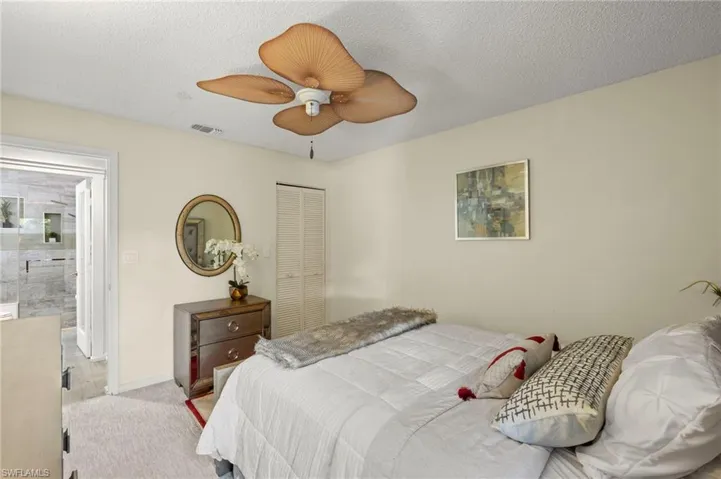 Carpeted bedroom featuring a textured ceiling, a closet, and ceiling fan.