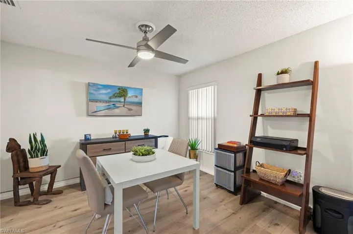 Versatile den/dining space featuring a textured ceiling, barn-style door, light wood-look flooring, and ceiling fan ideal as a dining room, den, or flexible living area.
