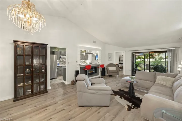 Living area with a chandelier, light wood-style flooring, and high vaulted ceiling