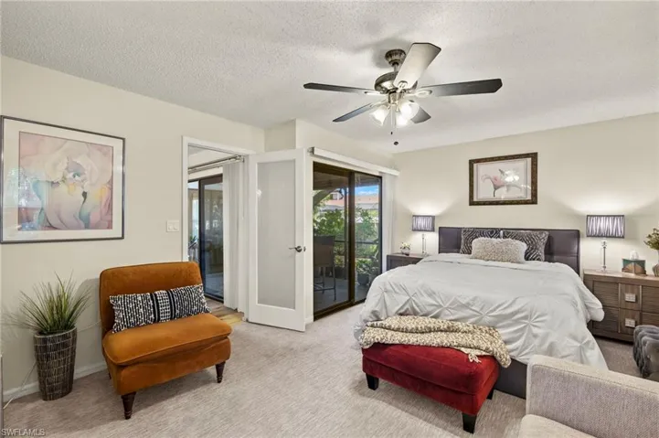 Carpeted bedroom with a textured ceiling, access to lanai, and ceiling fan