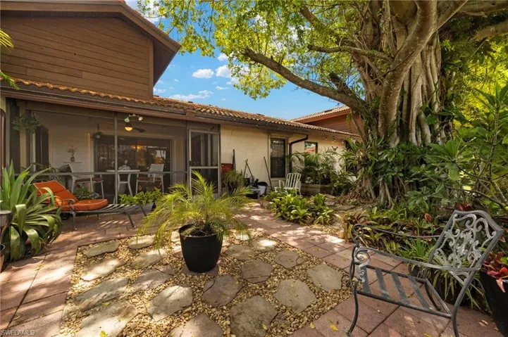 View of the screened lanai overlooking a private, tranquil backyard oasis framed by lush tropical landscaping.