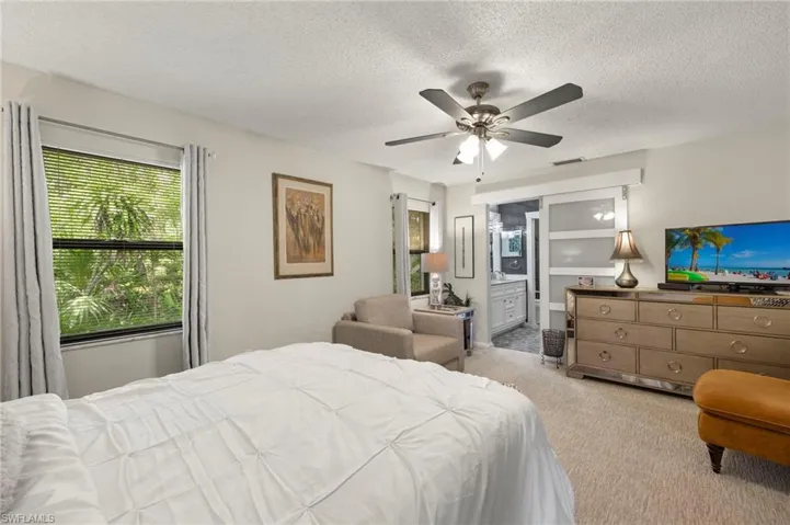 Bedroom featuring carpet flooring, a textured ceiling, a ceiling fan, and ensuite bath