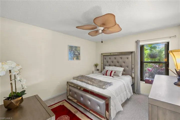 Carpeted guest bedroom with a textured ceiling and a ceiling fan with garden views