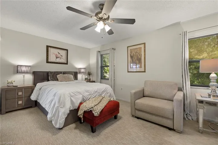 Bedroom featuring a textured ceiling, carpet floors, multiple windows, and ceiling fan