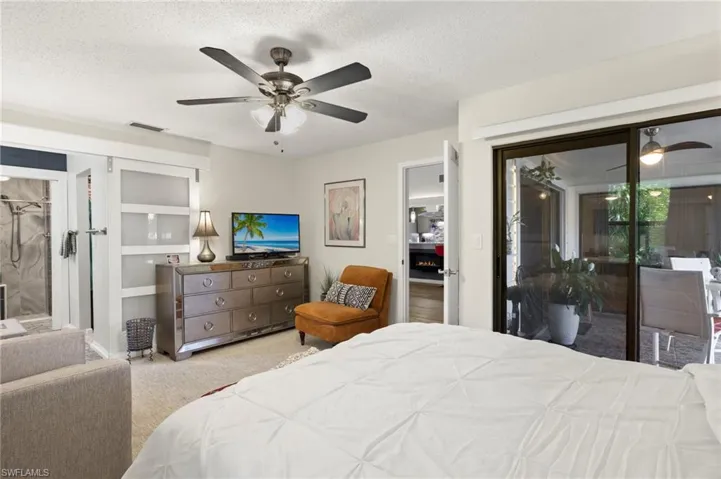Carpeted bedroom with a textured ceiling, ceiling fan, and access to exterior lanai