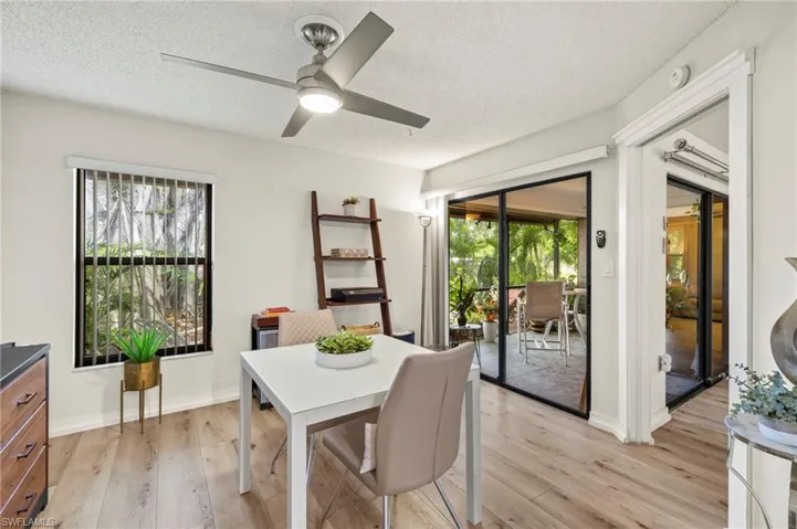 Versatile den/dining space featuring a textured ceiling, barn-style door, light wood-look flooring, and ceiling fan, ideal as a dining room, den, or flexible living area.
