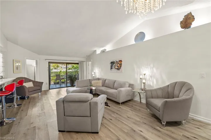 Living area featuring lofted ceiling, light wood-style floors, and a chandelier