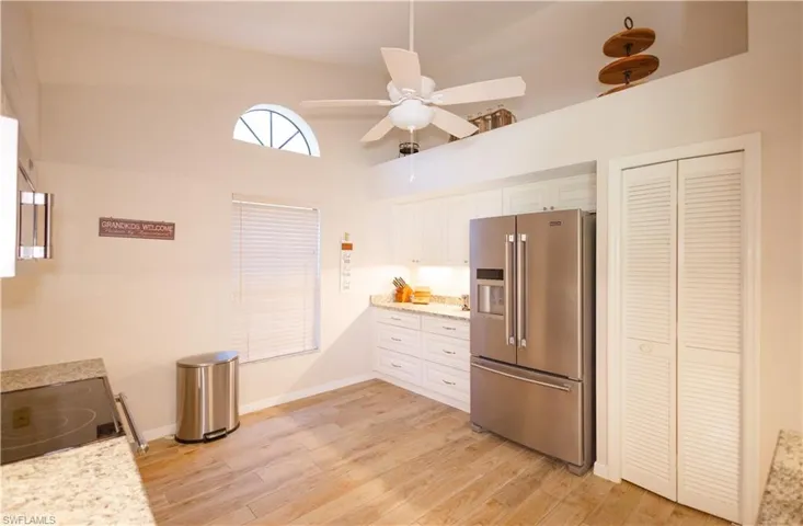 Kitchen featuring high end fridge, light hardwood / wood-style flooring, ceiling fan, high vaulted ceiling, and white cabinets