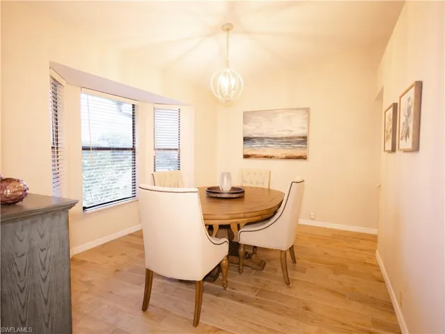 Dining space with light hardwood / wood-style flooring and an inviting chandelier