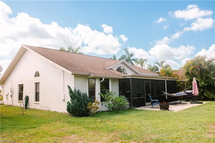 Rear view of house featuring a sunroom, a patio area, and a lawn