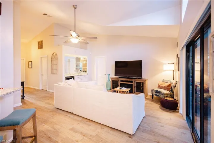 Living room featuring light hardwood / wood-style floors, high vaulted ceiling, and ceiling fan