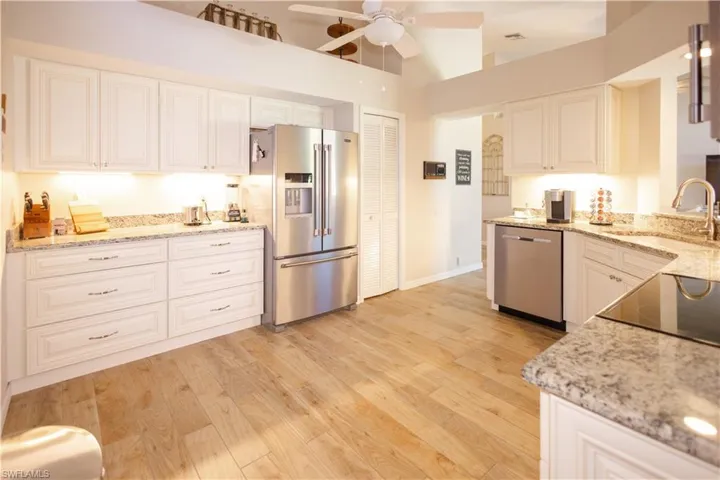 Kitchen with light stone countertops, ceiling fan, sink, and appliances with stainless steel finishes