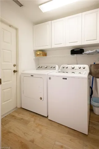 Laundry area featuring washer and dryer, light hardwood / wood-style flooring, and cabinets