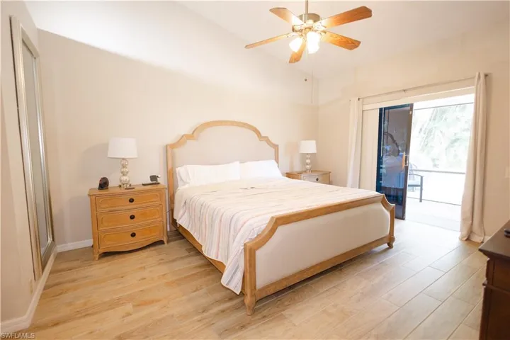 Bedroom featuring access to exterior, ceiling fan, vaulted ceiling, and hardwood / wood-style floors
