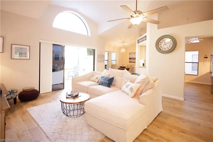 Living room with high vaulted ceiling, ceiling fan, and light wood-type flooring