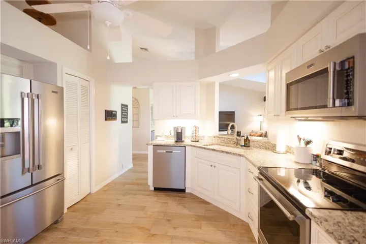 Kitchen with ceiling fan, sink, white cabinets, and appliances with stainless steel finishes