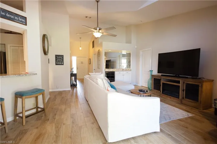 Living room featuring high vaulted ceiling, light wood-type flooring, wine cooler, and ceiling fan