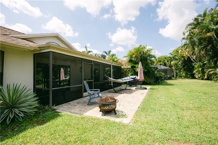 View of yard with a patio area, a sunroom, and a fire pit