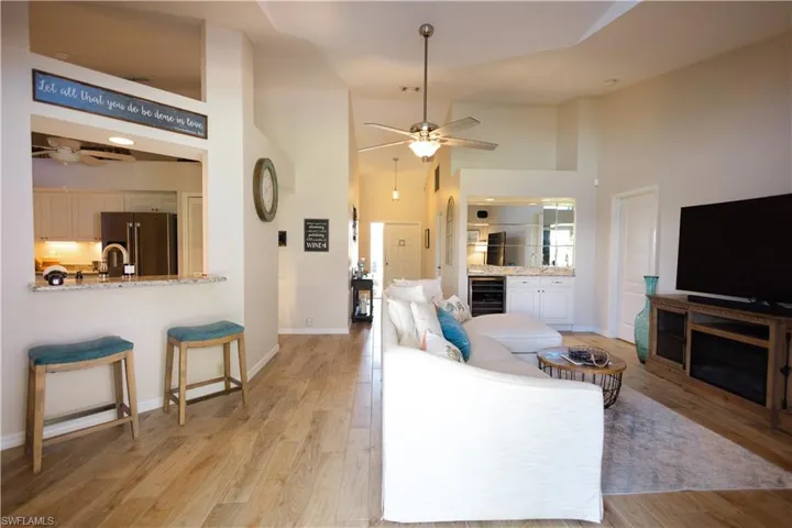 Living room with high vaulted ceiling, beverage cooler, ceiling fan, and light wood-type flooring