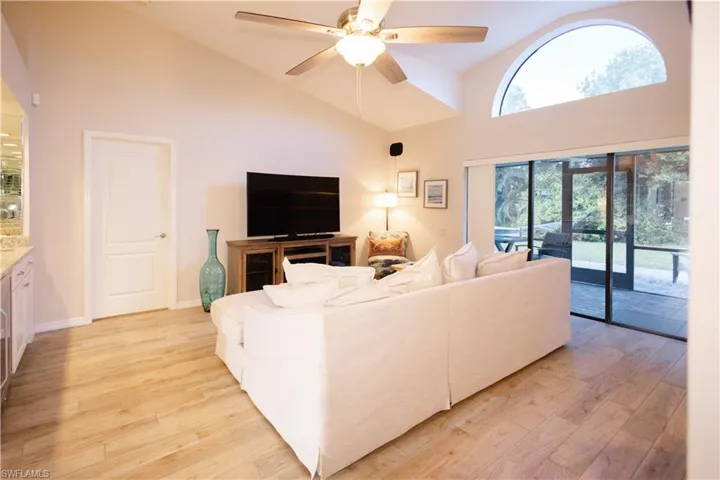 Living room featuring high vaulted ceiling, ceiling fan, and light hardwood / wood-style flooring