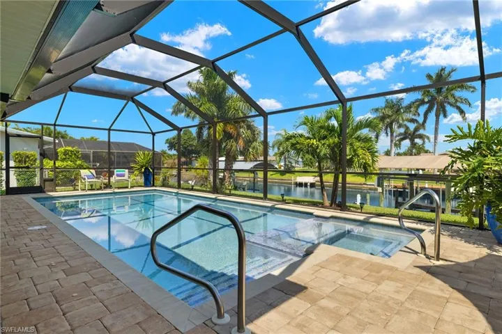 View of pool featuring a lanai, a patio, an in ground hot tub, and a water view
