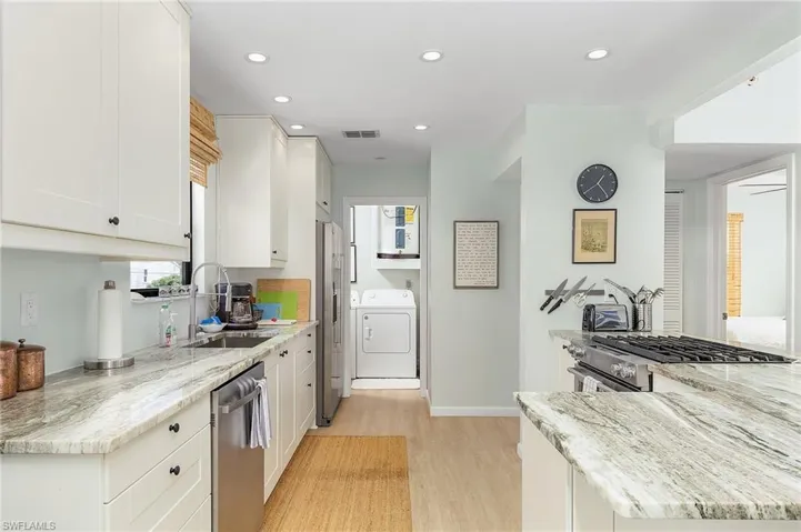 Kitchen with stainless appliances, and laundry room in the background.
