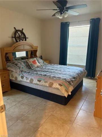 Bedroom featuring ceiling fan, light tile patterned floors, and a textured ceiling