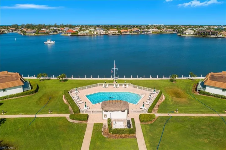 Aerial perspective of suburban area featuring a nearby body of water and a pool area