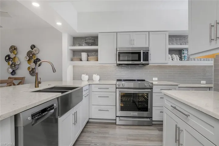 Kitchen featuring open shelves, appliances with stainless steel finishes, light stone countertops, recessed lighting, and decorative backsplash