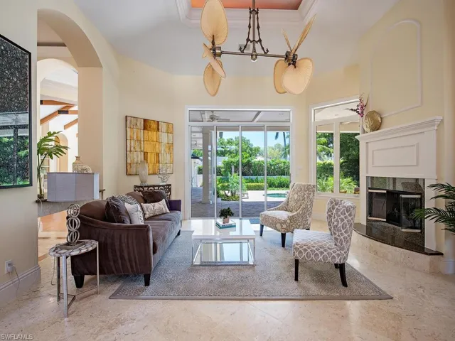 Living room with arched walkways, a premium fireplace, crown molding, and a sunroom
