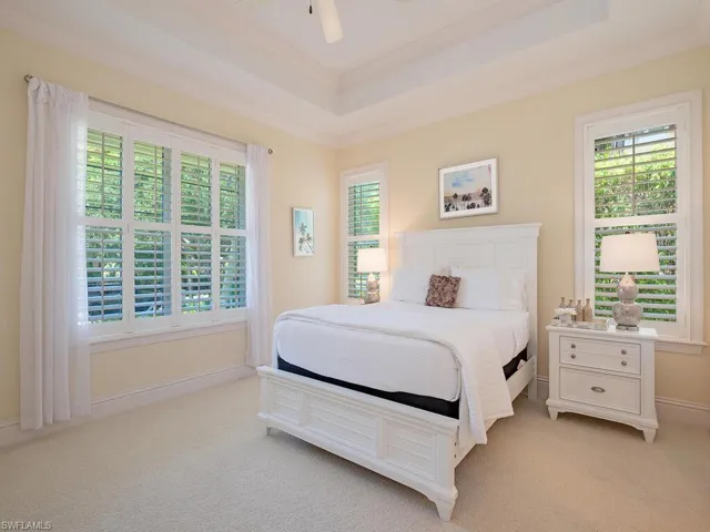 Bedroom featuring a tray ceiling, light carpet, a ceiling fan, and crown molding