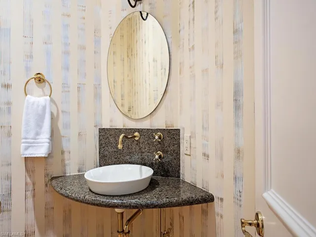 Half bathroom featuring a sink and wallpapered walls