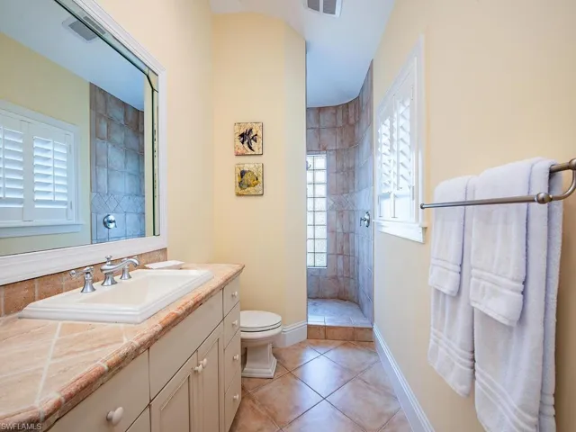 Bathroom featuring vanity, walk in shower, and light tile patterned floors