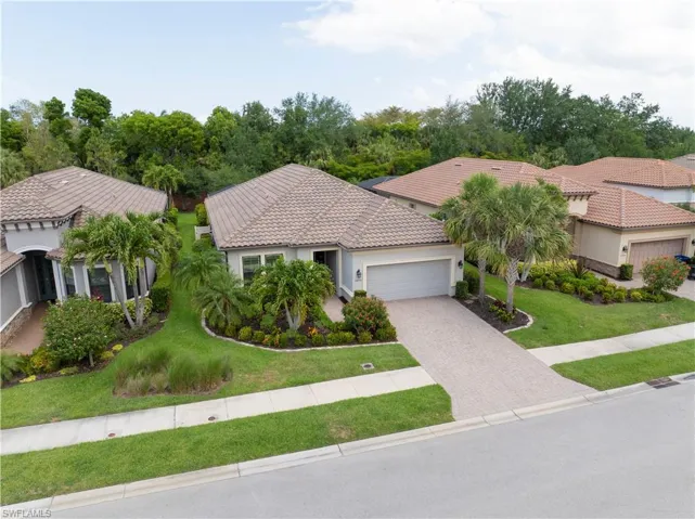 Mediterranean / spanish home featuring a garage, a tiled roof, a front lawn, driveway, and stucco siding
