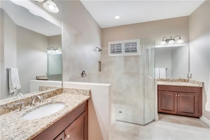 Bathroom featuring walk in shower, two vanities, and tile patterned flooring