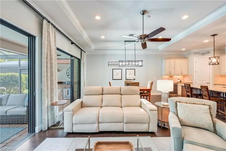 Living room featuring ceiling fan, a tray ceiling, recessed lighting, and ornamental molding