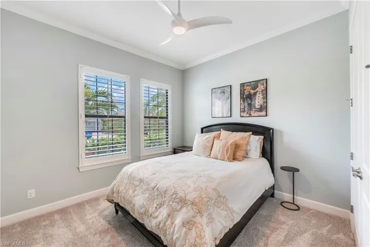 Carpeted bedroom featuring baseboards, ornamental molding, and ceiling fan