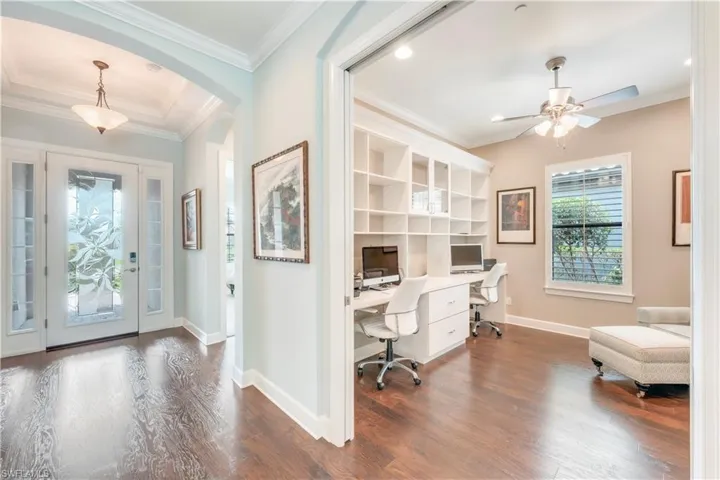 Entrance foyer with ceiling fan, dark wood-style flooring, ornamental molding, arched walkways, and baseboards