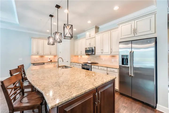 Kitchen featuring stainless steel appliances, a sink, light stone counters, crown molding, and tasteful backsplash