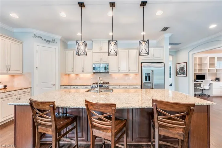Kitchen with stainless steel appliances, a spacious island, backsplash, hanging light fixtures, and recessed lighting