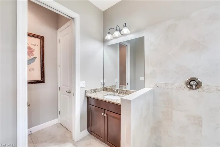 Bathroom with vanity, tile patterned floors, and a tile shower