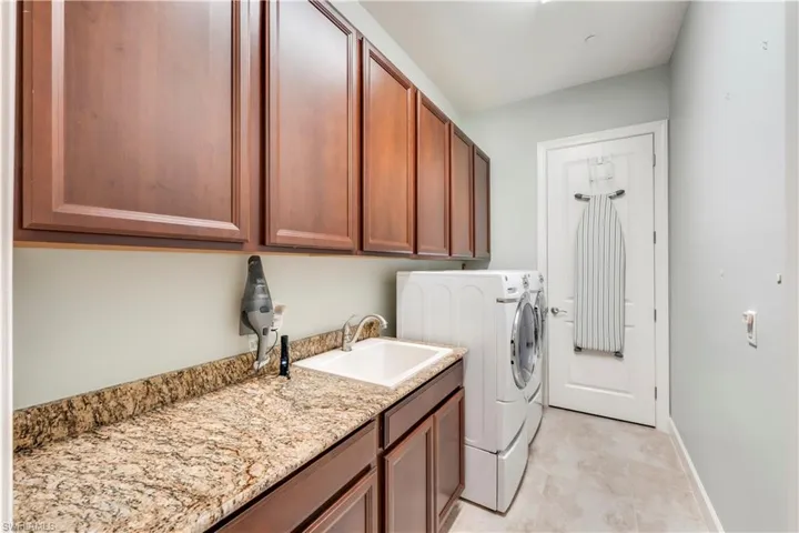 Washroom with independent washer and dryer, cabinet space, and baseboards