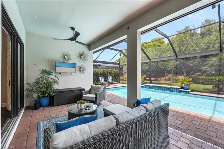 Swimming pool with an outdoor living space, a patio, glass enclosure, and a ceiling fan