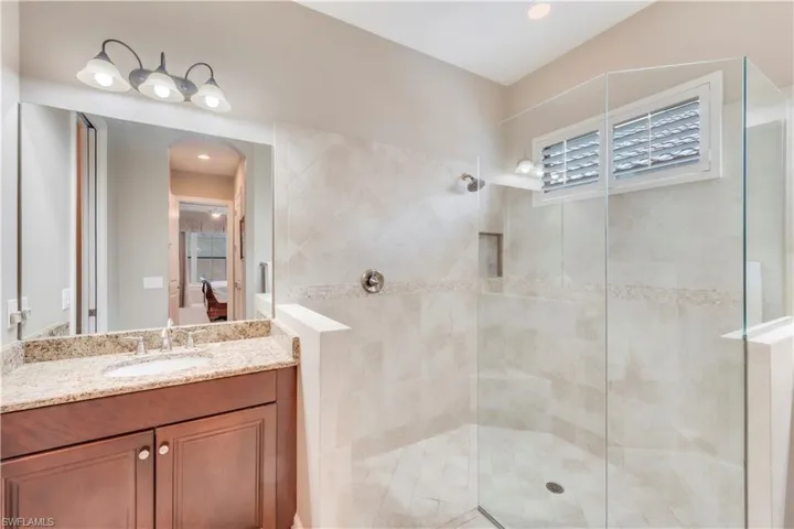 Ensuite bathroom featuring a tile shower and vanity
