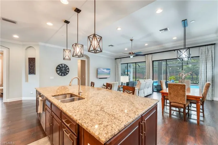Kitchen with a sink, dark wood-type flooring, crown molding, baseboards, and recessed lighting