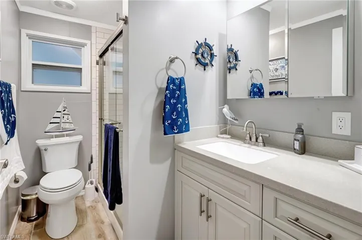 Bathroom with hardwood / wood-style floors, vanity, toilet, and an enclosed shower