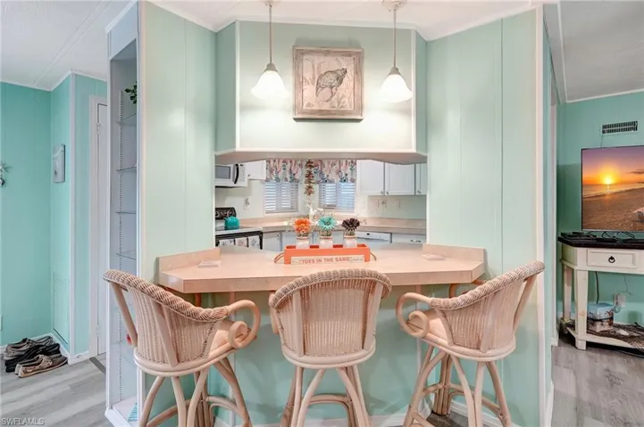 Dining area with ornamental molding and light hardwood / wood-style flooring